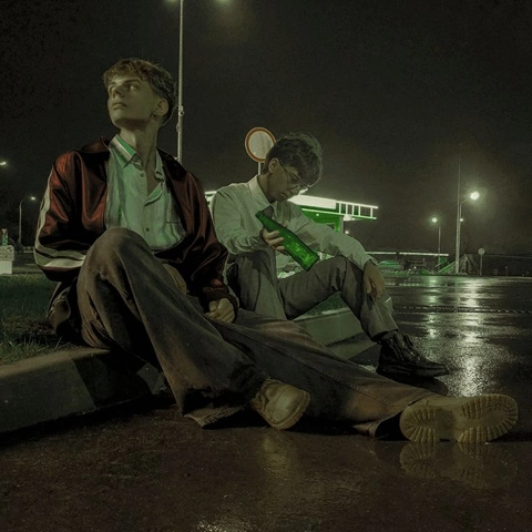 A group of men sitting on the side of a road.