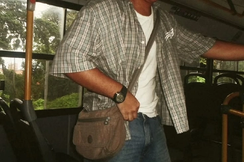 A man in a plaid shirt is holding a brown bag.