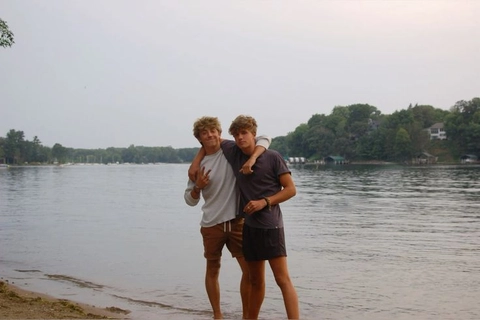A group of young men standing next to a body of water.