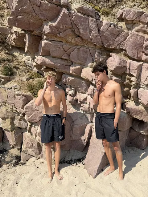 A couple of men standing next to each other on a beach.