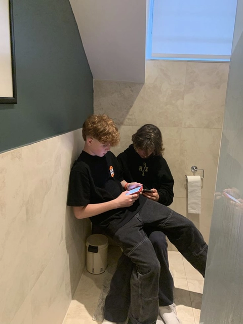 A group of people sitting on top of a toilet.
