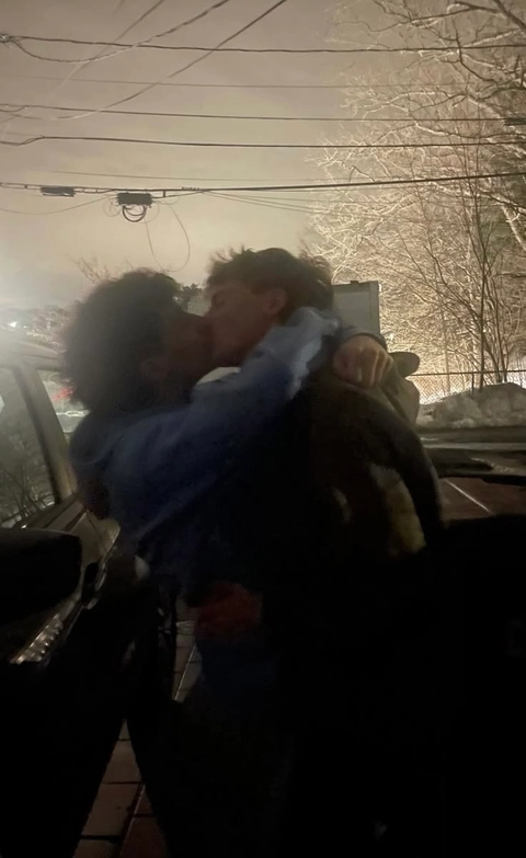 A couple of people standing next to each other near a car.