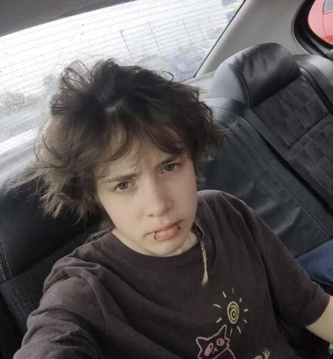 A young boy with a mohawk sitting in the back seat of a car.