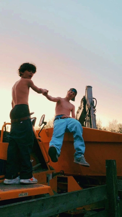 A couple of boys sitting on top of a truck.