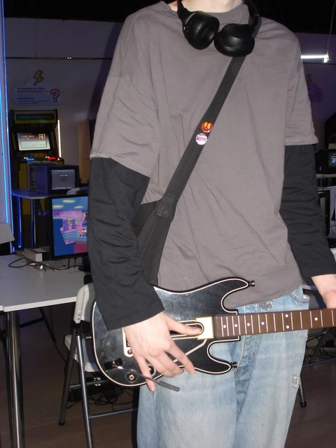 A mannequin wearing headphones and holding a guitar.