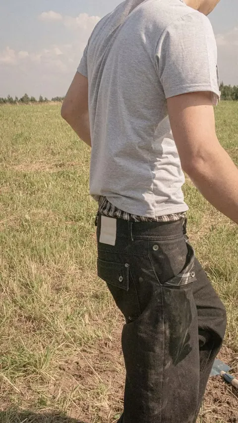 A man standing in a field with his back to the camera.