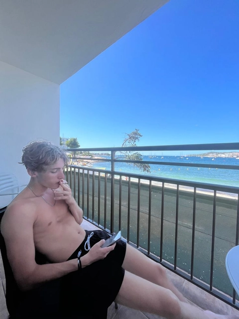 A man sitting on a balcony next to a swimming pool.