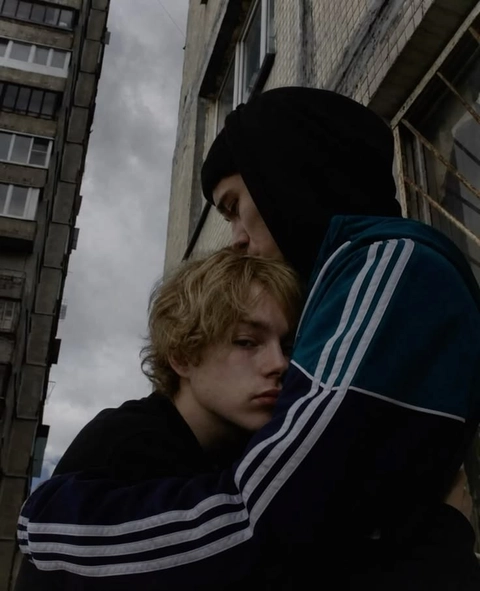A man and a boy are standing in front of a building.