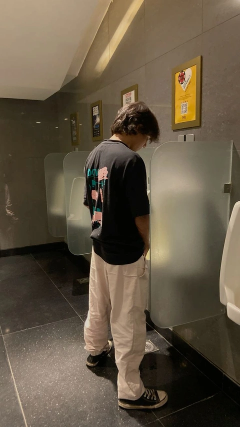 A man standing in front of a row of toilets.
