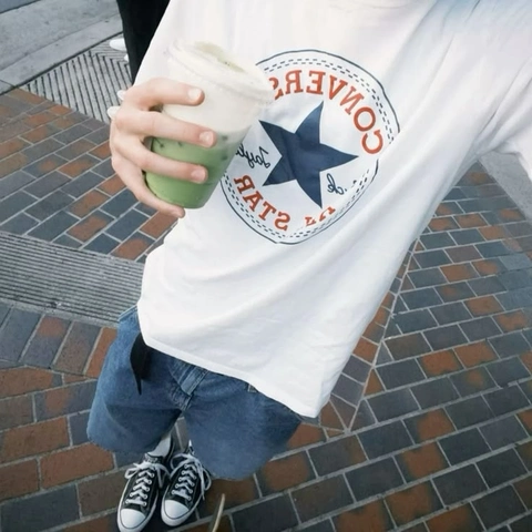 A person holding a cup of green juice in their hand.