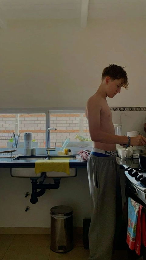 A shirtless man standing in front of a sink.
