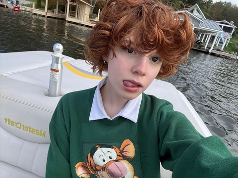 A young boy in a green sweater with a teddy bear on his sweater.