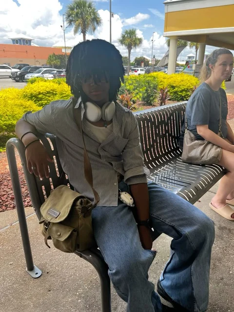 A mannequin sitting on a bench with headphones on.