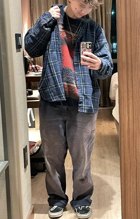 A man standing in front of a mirror holding a cell phone.