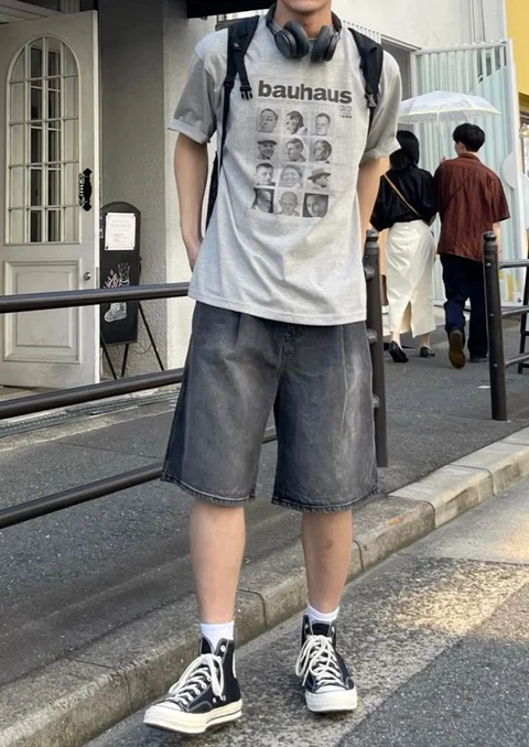 A man wearing headphones and a t-shirt with a picture of a group of people.
