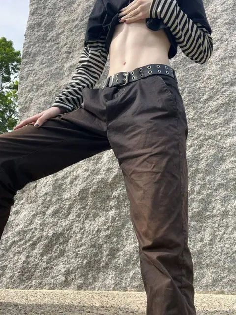 A man in a black and white striped shirt and brown pants.