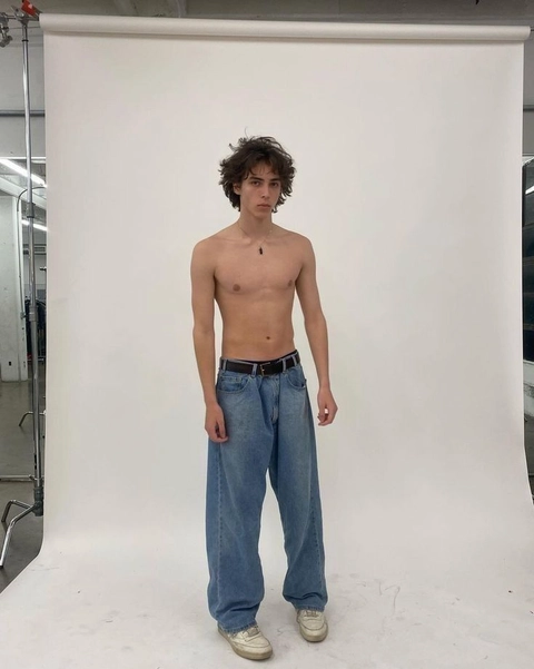 A shirtless young man standing in front of a mirror.