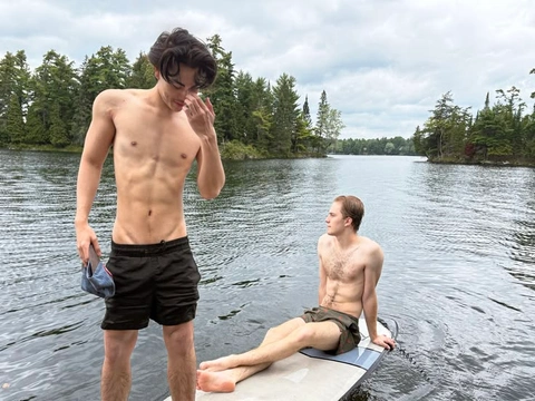A group of men standing on top of a surfboard in the water.