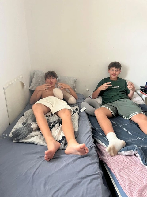 A group of young men laying on top of a bed.