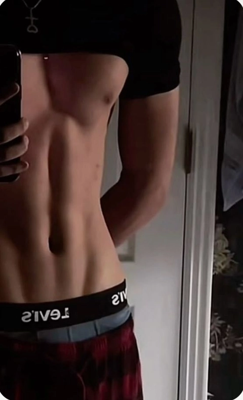 A shirtless man standing in front of a mirror.