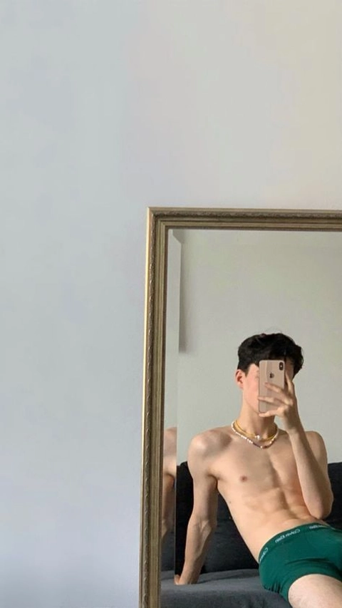 A shirtless man taking a selfie in front of a mirror.
