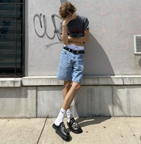A man standing in front of a wall with graffiti on it.