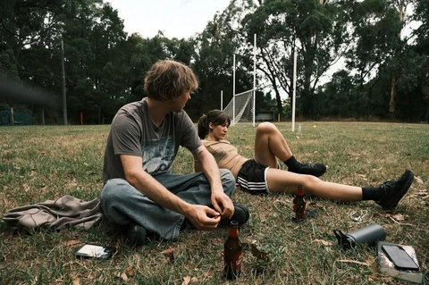 A couple of people sitting on top of a grass covered field.