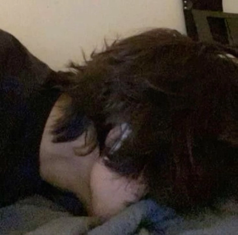 A woman laying on top of a bed next to a pillow.