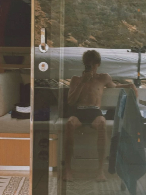 A man sitting on a chair in front of a mirror.
