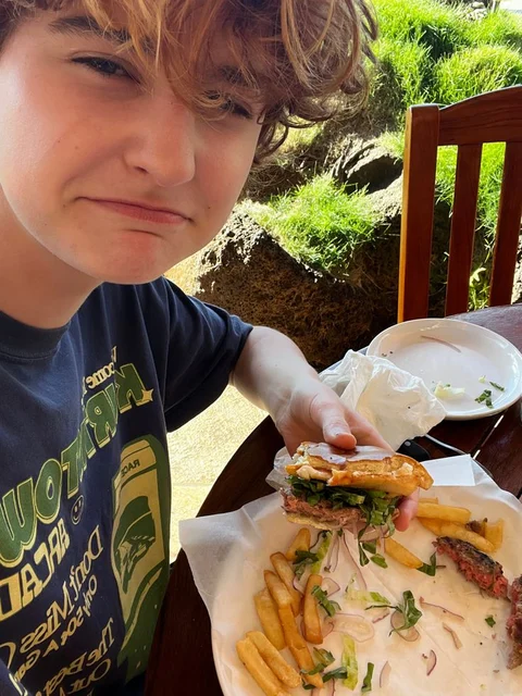 A young boy holding a hamburger and french fries.