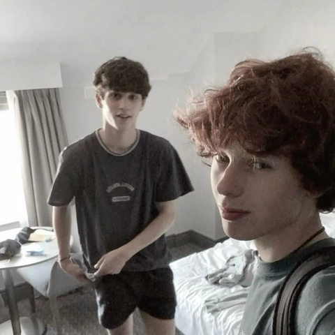 A couple of young men standing next to each other in a room.