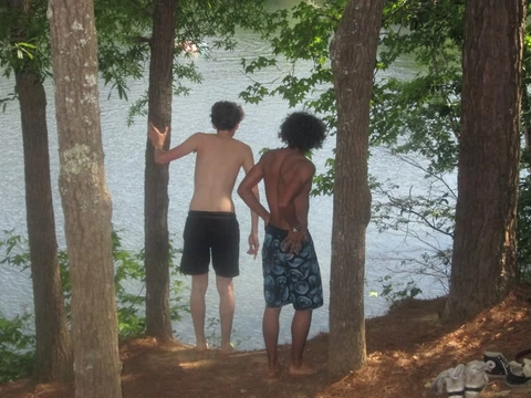 A group of three men standing next to each other in the woods.