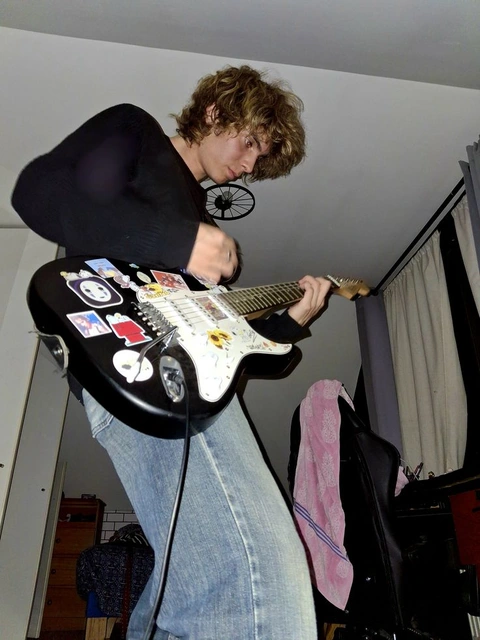 A man holding a guitar with stickers on it.