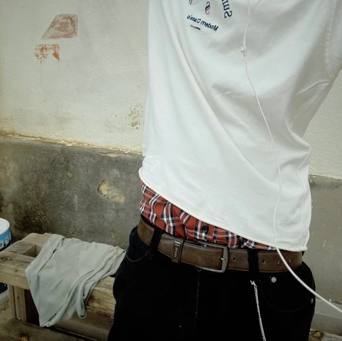A man wearing a white shirt and plaid shirt with a belt.