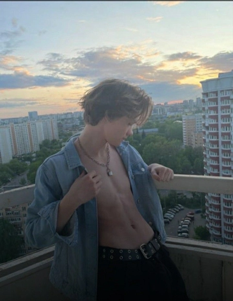A shirtless man standing on top of a balcony.
