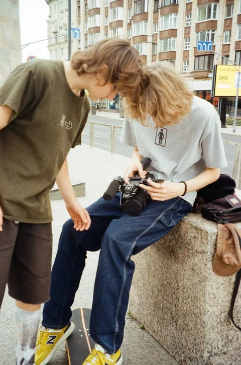 A couple of people sitting on top of a cement wall.