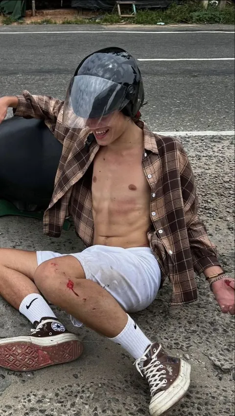 A shirtless man sitting on the ground with a helmet on.
