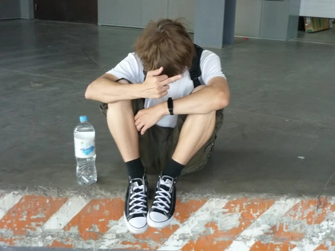 A man sitting on the ground with his head in his hands.