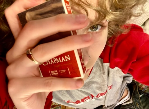 A woman holding a box of chapman cigarettes in her hands.