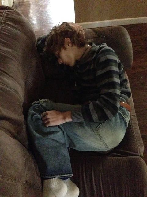 A man sitting on top of a brown couch.