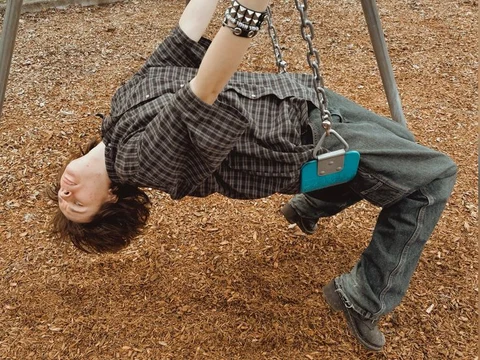 A man hanging upside down on a swing set.