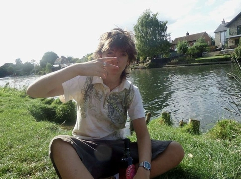A man sitting on the grass next to a body of water.