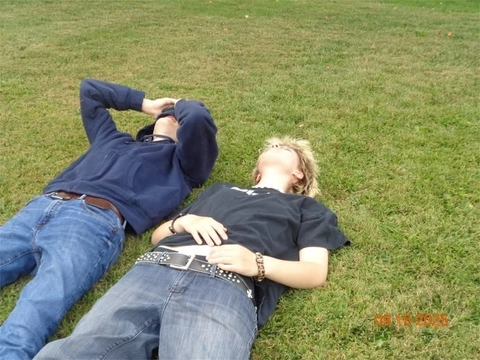 A couple of people laying on top of a lush green field.