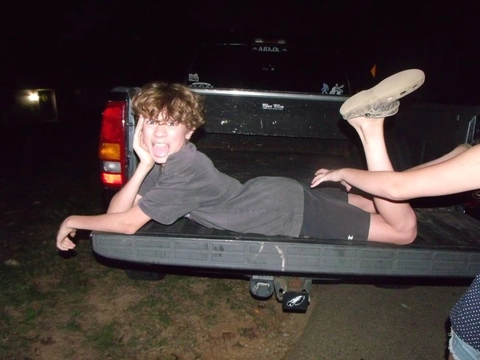 A man laying on top of a truck with his feet up.