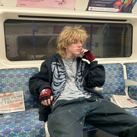 A man sitting on a subway train talking on a cell phone.