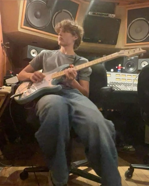 A man sitting on a chair playing a guitar.