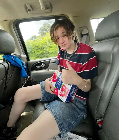 A young man sitting in the back seat of a car holding a box of cigarettes.