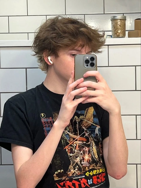 A young man taking a selfie in a bathroom mirror.