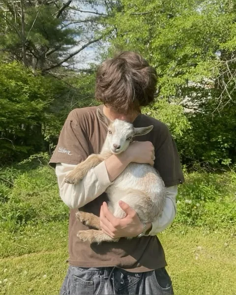 A man holding a baby goat in his arms.
