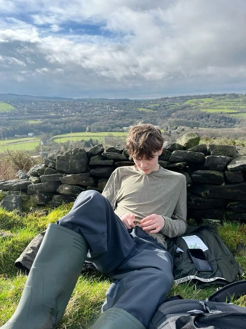 A young man sitting on top of a grass covered field.